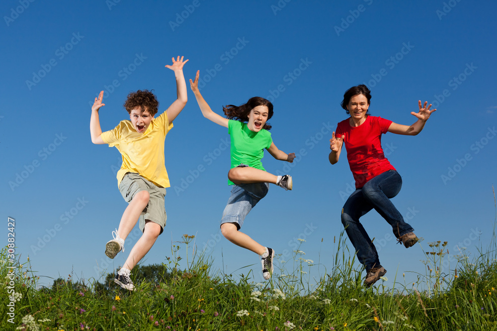Active family - mother and kids jumping outdoor