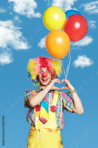 Portrait clown with balloons against the blue sky