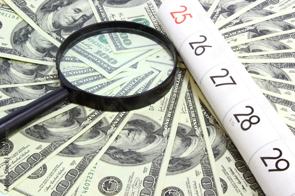 money bill magnifying glass and calendar