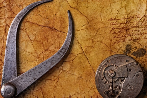 Antique tongs with a gears on the old textured paper