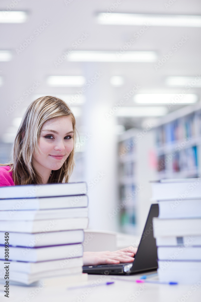 in the library - pretty, female student with laptop and books in the library - pretty, female student with laptop and books