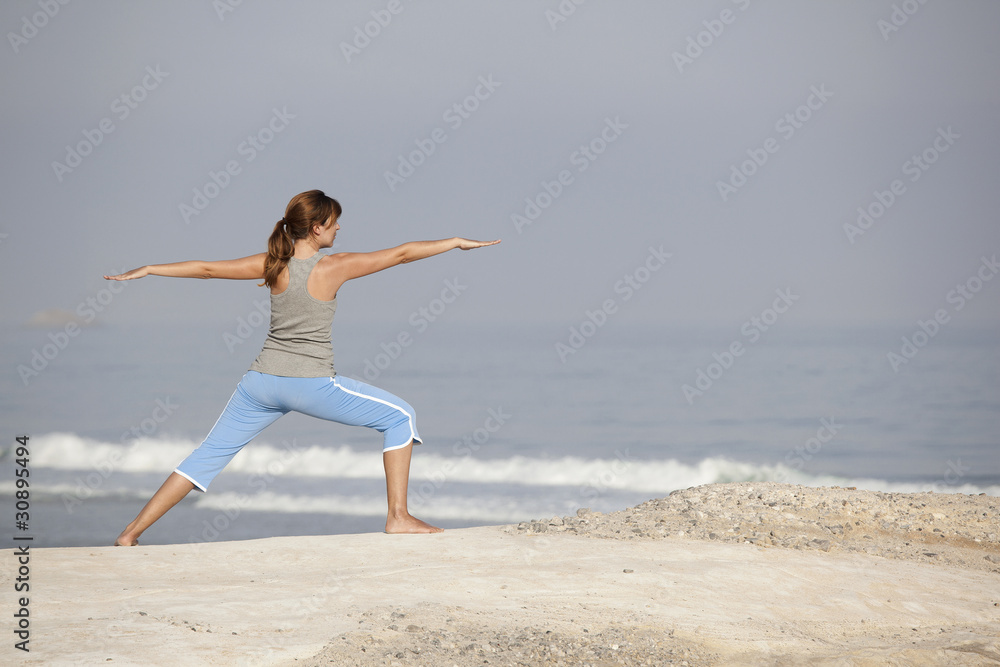 Beautiful young woman with arms open, relaxing on the beach