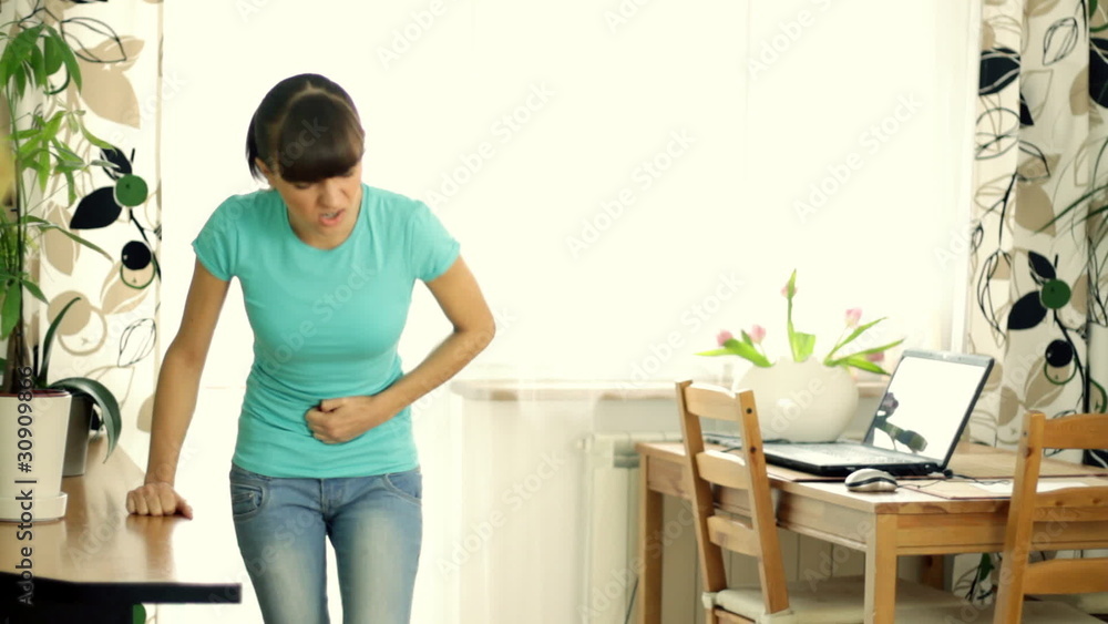 Young woman suffering from stomachache during homework Young woman suffering from stomachache during homework