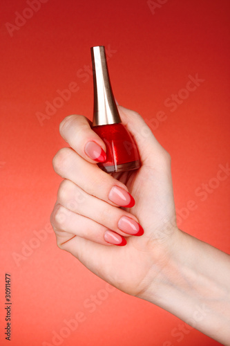 nail polish in hand on a red background