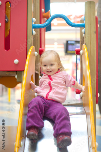 adorable baby sliding down baby slide on playground in mall