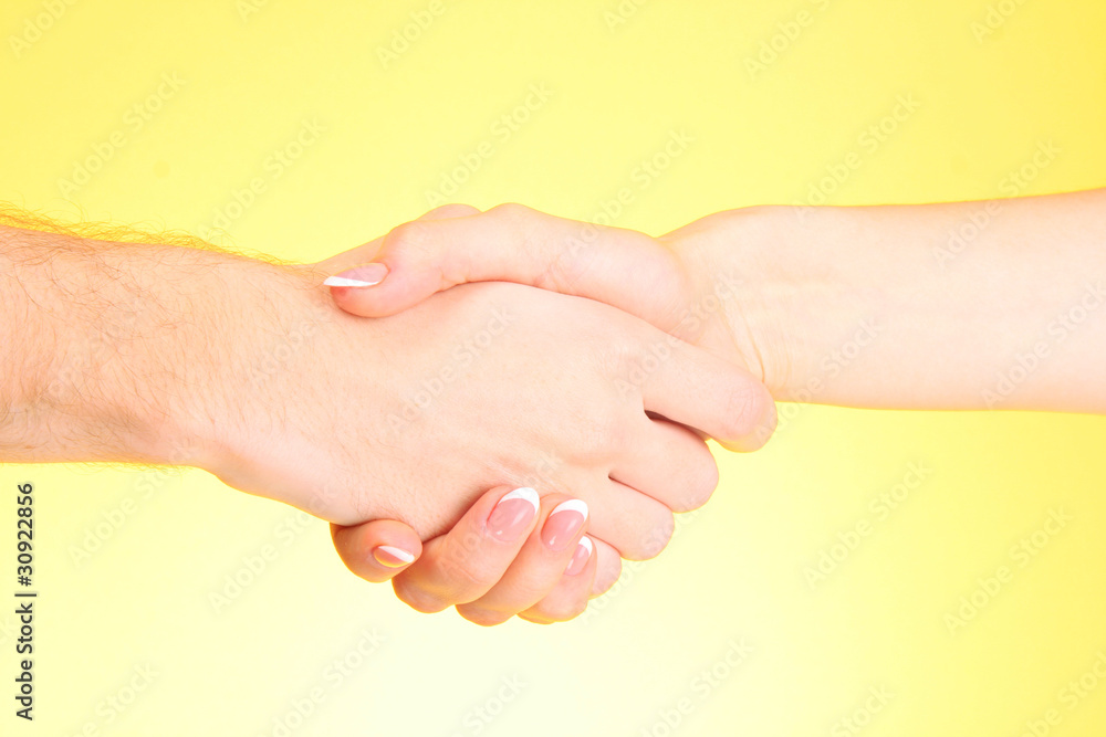 handshake between man and woman on yellow background handshake between man and woman on yellow background