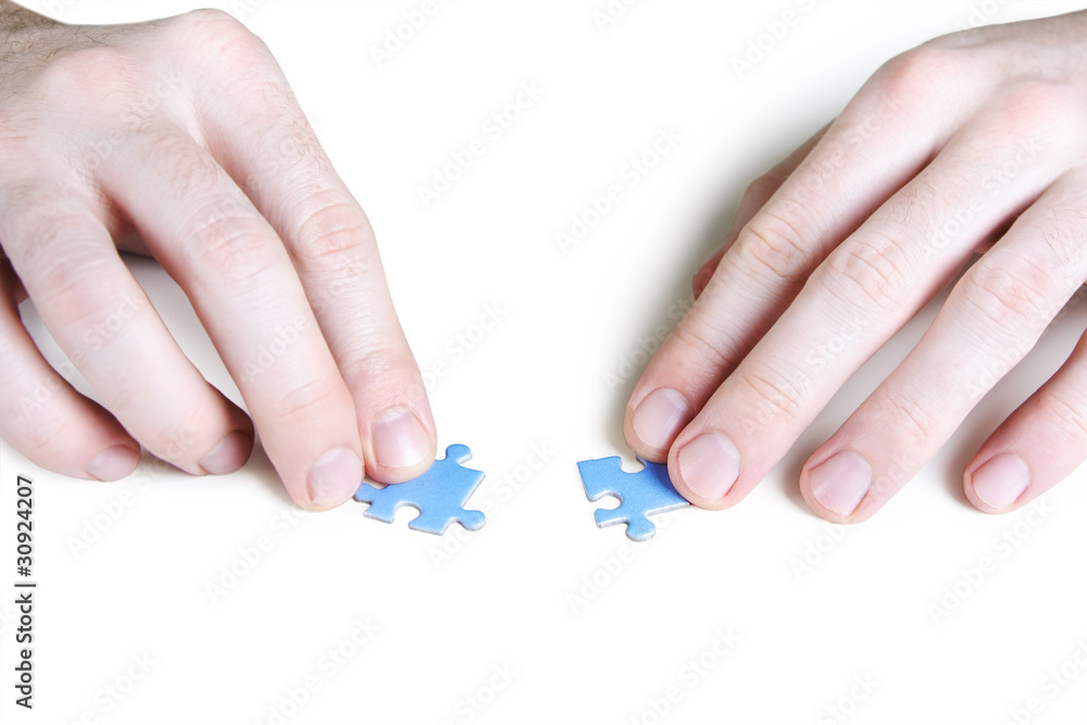 closeup of mans hands assembling two blue puzzle pieces, isolate closeup of mans hands assembling two blue puzzle pieces, isolate