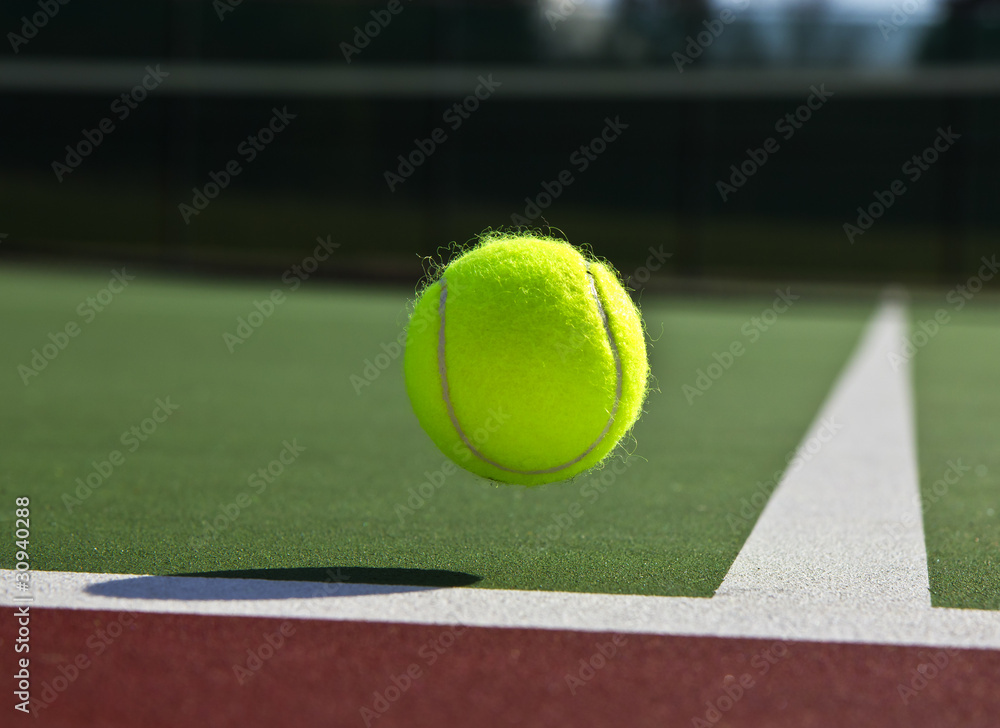 Tennis ball landing just inside outdoor court 