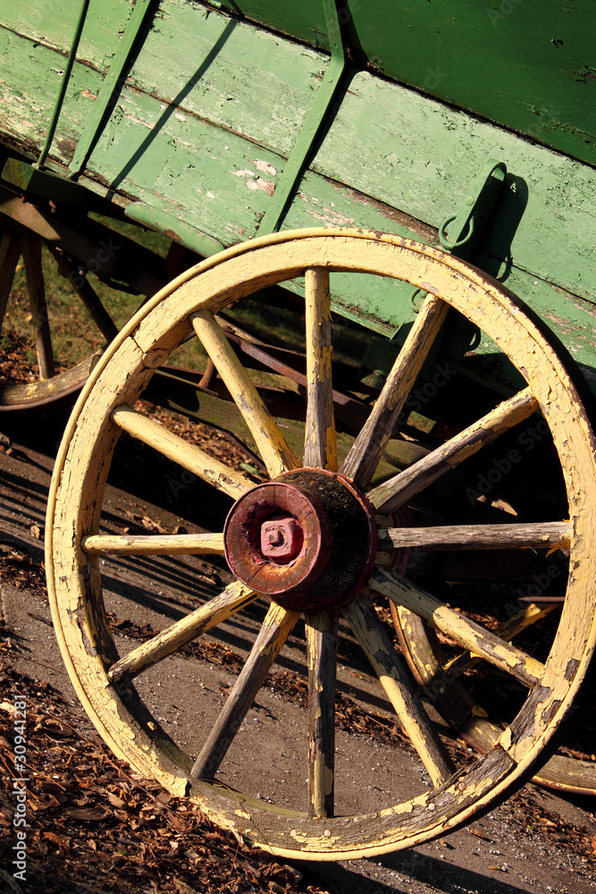 Rustic yellow wagon wheel on green cart