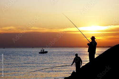 Fisherman silhouettes against sunset