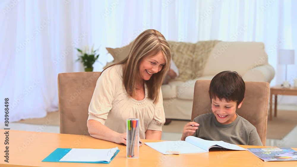 A boy doing his homeworks with his grandmother A boy doing his homeworks with his grandmother