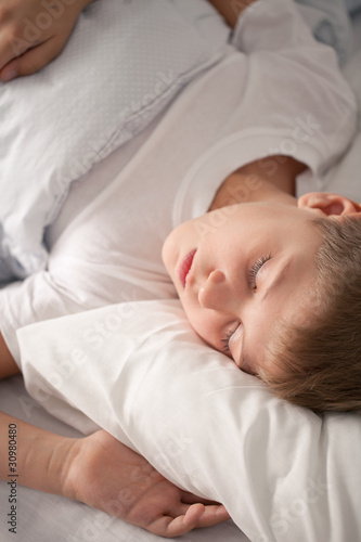 Charming little boy sleeping on the bed