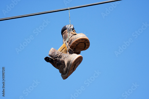 Worn out boots hanging over power line photo