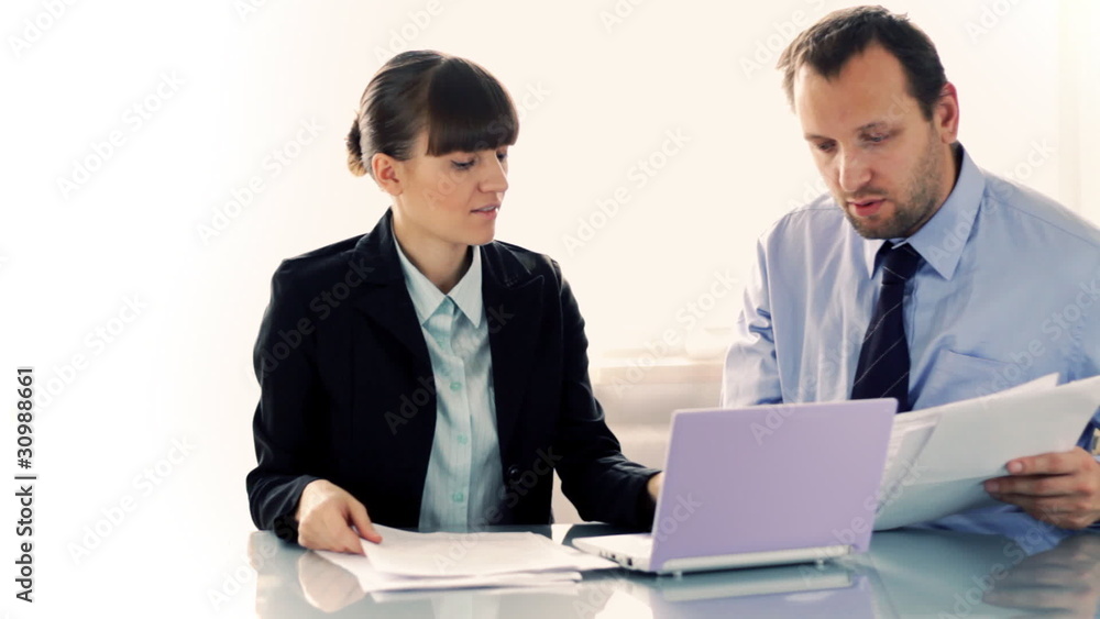 Young business couple working with documents and laptop Young business couple working with documents and laptop