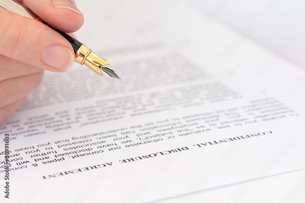 Hand with Pen Checking Disclosure Agreement Hand with Pen Checking Disclosure Agreement