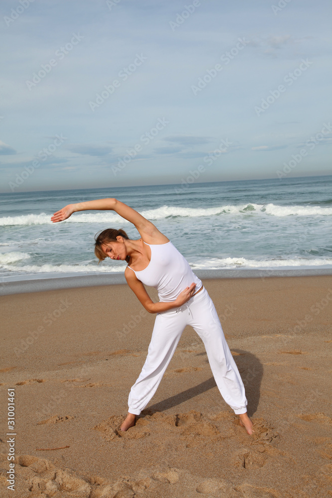 Beautiful blond woman doing stretching exercises on the beach Beautiful blond woman doing stretching exercises on the beach