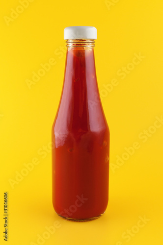 Ketchup in a bottle on yellow background.