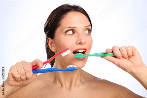 Fun young woman with three toothbrushes