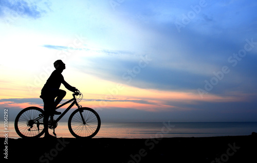 Silhouette of man riding bicycle with beautiful lake near by at