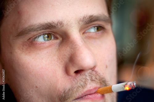 The middle-age man smokes a cigarette. Focus on the eyes.
