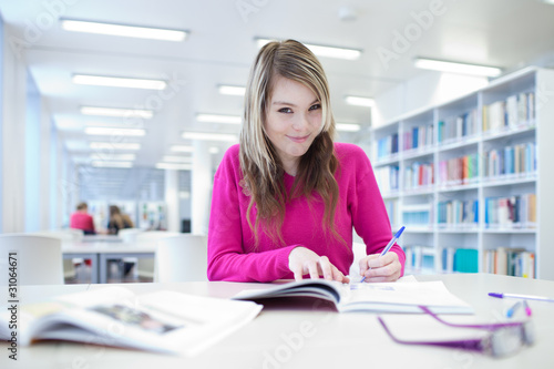 in the library - pretty, female student with laptop and books