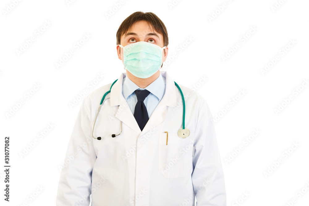 Medical doctor in mask looking up isolated on white. Medical doctor in mask looking up isolated on white.