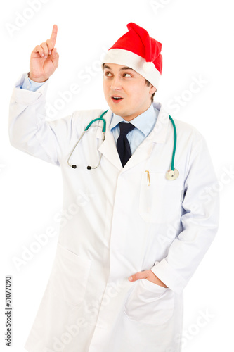 Surprised doctor in Santa hat with rised finger. Idea gesture.