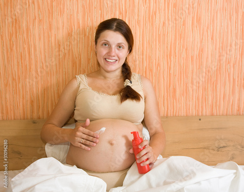 pregnant woman rubs cream photo