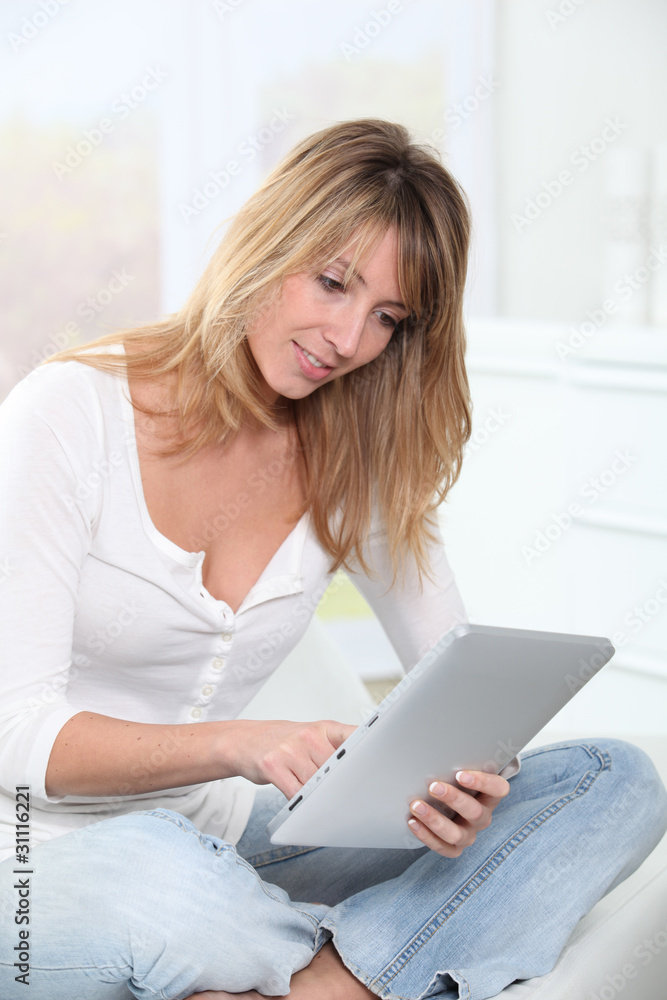 Blond woman using electronic tablet at home Blond woman using electronic tablet at home