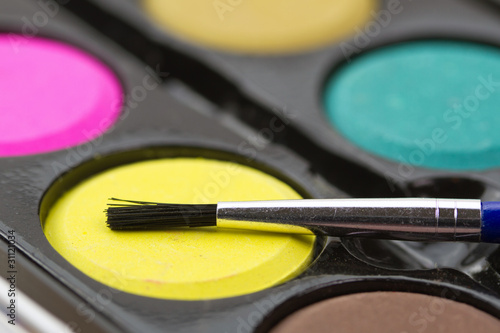 Closeup of a palette of watercolor paints with red brush.