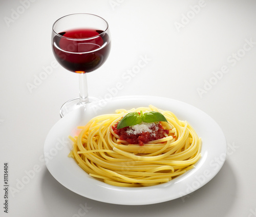 piatto di spaghetti al pomodoro con bicchiere di vino rosso