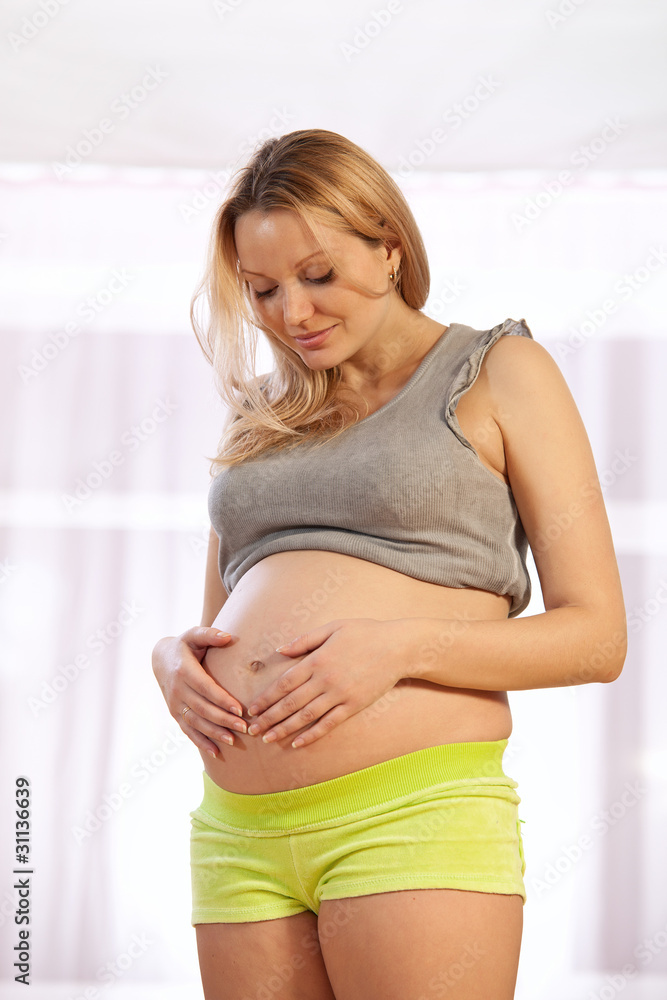 Portrait of young pregnant woman looking at her tummy Portrait of young pregnant woman looking at her tummy