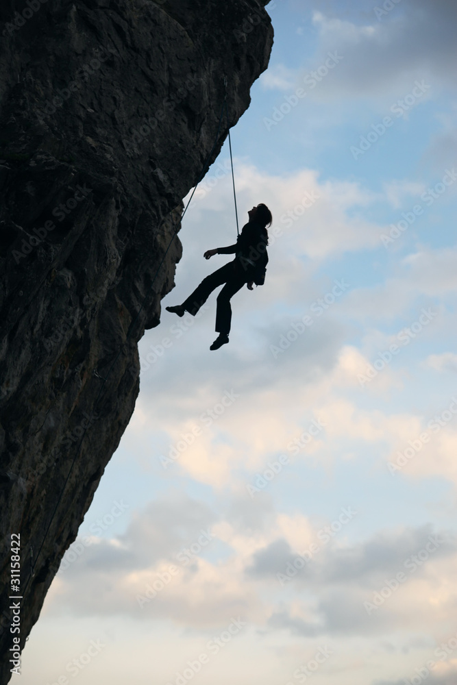 Silhouette of rock climber going down after reaching the top Silhouette of rock climber going down after reaching the top