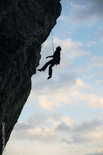 Silhouette of rock climber going down after reaching the top
