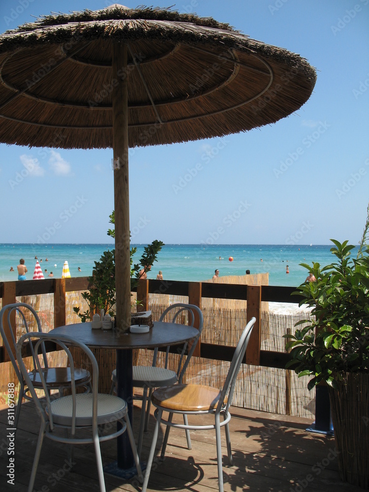 Coffee table of the beach pub, with wicker umbrella