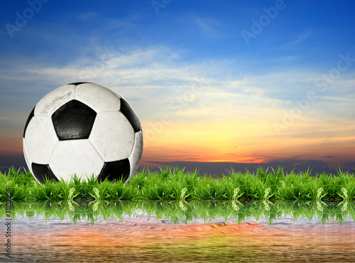 football in green grass over a sunset sky