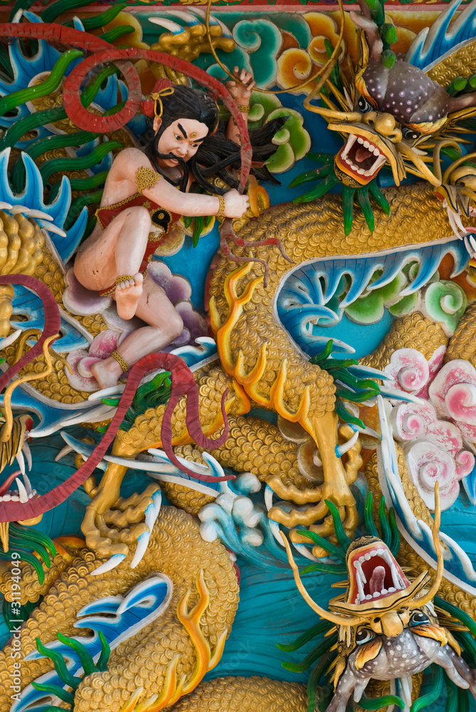 Fototapeta premium Chinese god fight to the dragon on temple wall, Thailand