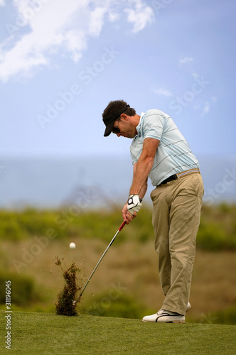Golfer hitting iron shot from fairway