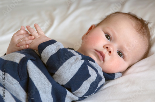 Serious baby lying with crossed fingers