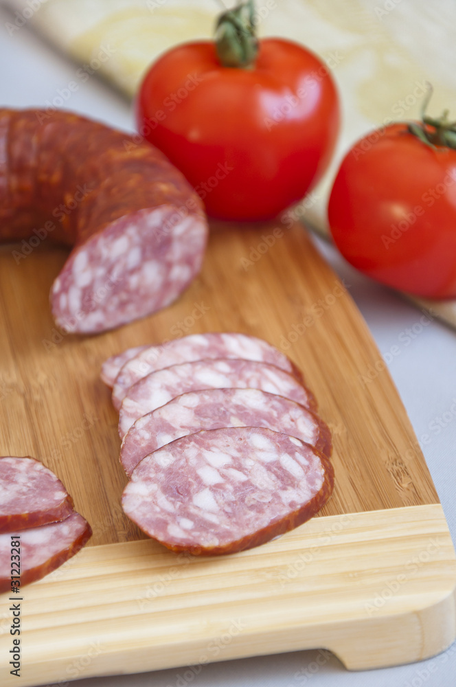 Smoked sausage on a cutting board and fresh tomatoes Smoked sausage on a cutting board and fresh tomatoes