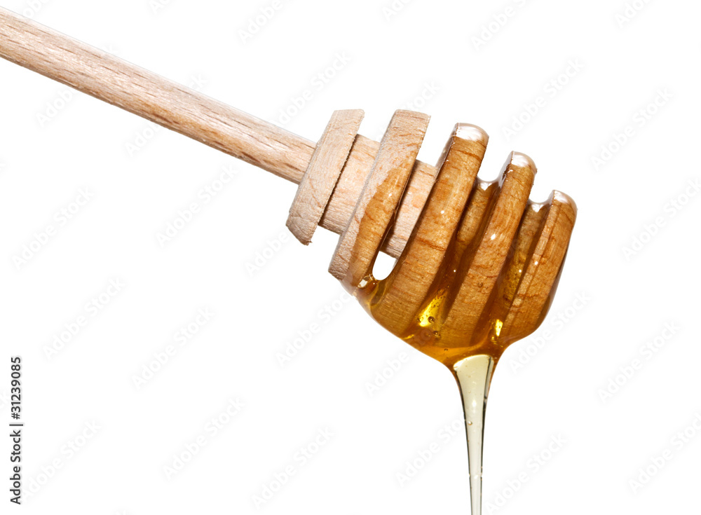 Golden honey on the wooden dipper over white background Golden honey on the wooden dipper over white background
