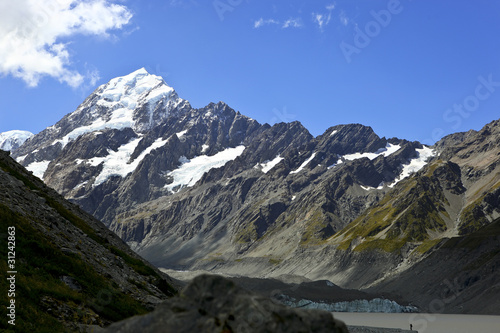 New Zealand Mt Cook with snow covered peak blue sky and large lake at the foot of the mountain range.