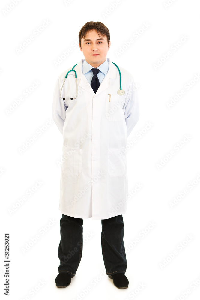 Smiling medical doctor holding hands behind his back Smiling medical doctor holding hands behind his back