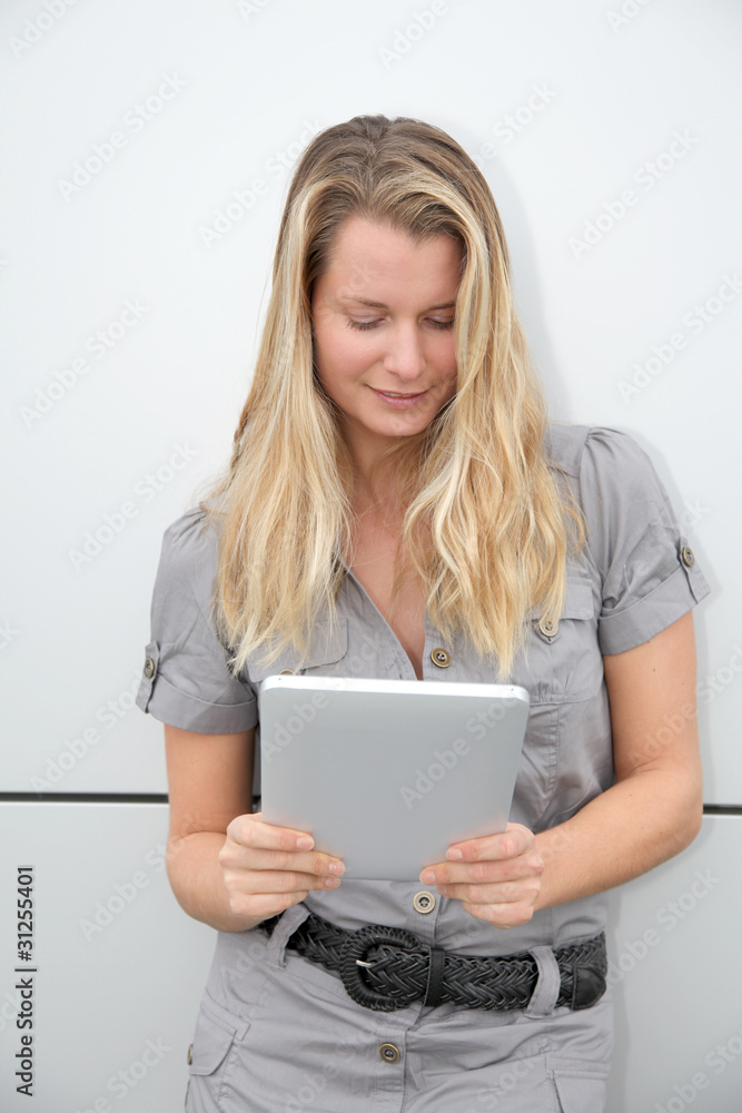 Beautiful blond woman using touchpad on grey background
