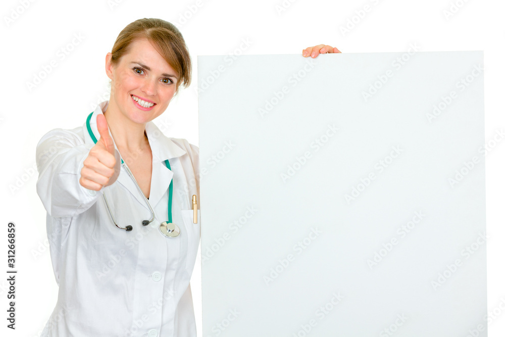 Female doctor holding blank billboard and showing thumbs up Female doctor holding blank billboard and showing thumbs up