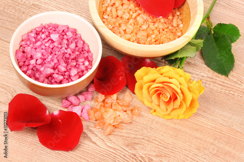 Bath aromatic salt, rose and petals on wooden background