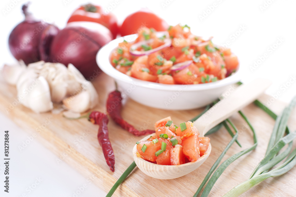 Salsa in a bowl on a wooden board and ingredients