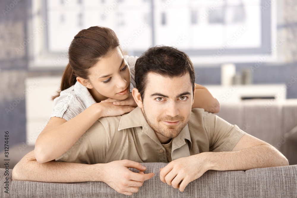 Happy couple sitting on sofa hugging each other Happy couple sitting on sofa hugging each other
