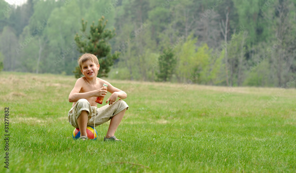 little boy with a ball sitting on the gass little boy with a ball sitting on the gass