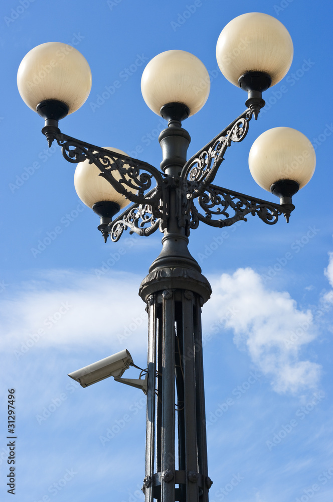Old stylized street lantern with security camera